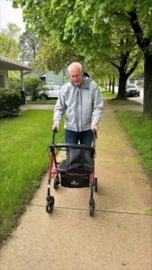 David using his rollator walker along a sidewalk