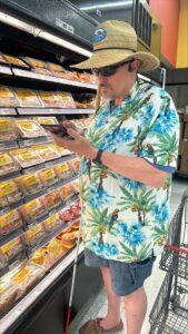 Kevin holding his white cane in a grocery store isle