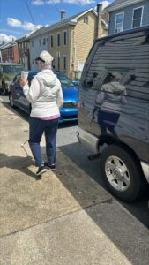 Sandy walking with her white cane in hand and a coffee cup in the other