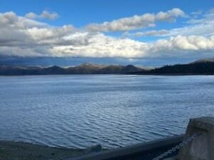 A body of water with mountains in the distance and blue skies.