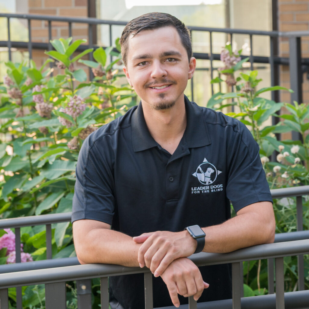 A man with dark short hair, mustache and goatee smiles toward the camera.
