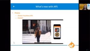 A presentation slide highlights updates about APS, featuring a video thumbnail of a person walking and a mobile app interface related to pedestrian safety.