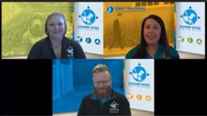 Three individuals are participating in a virtual meeting, each positioned against colorful, branded backgrounds featuring elements related to service dog training.