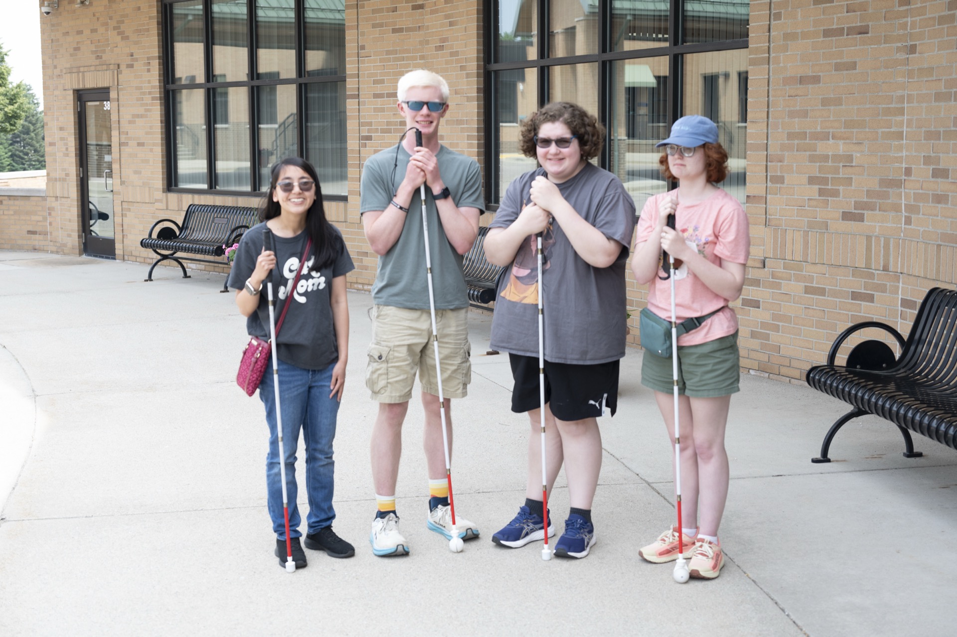 A group stands outside a building, each holding a white cane and wearing casual clothing, showcasing a sense of camaraderie.