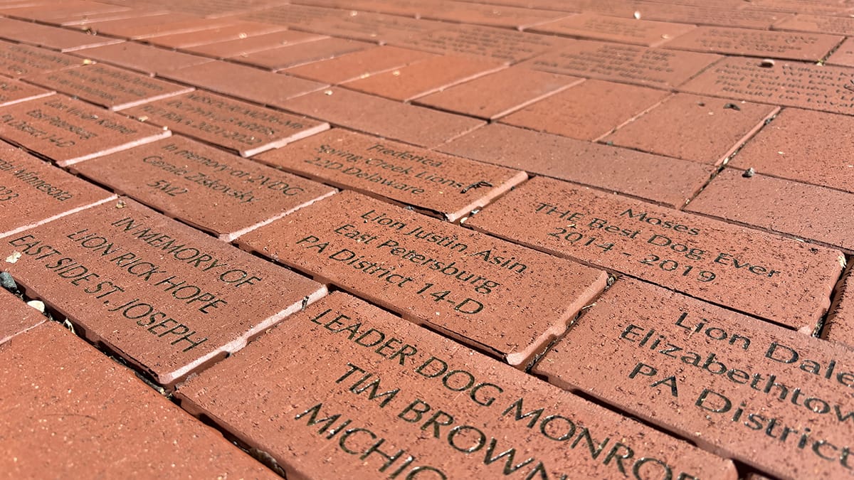 A pathway of engraved bricks commemorates various individuals and organizations, showcasing names and messages of remembrance.