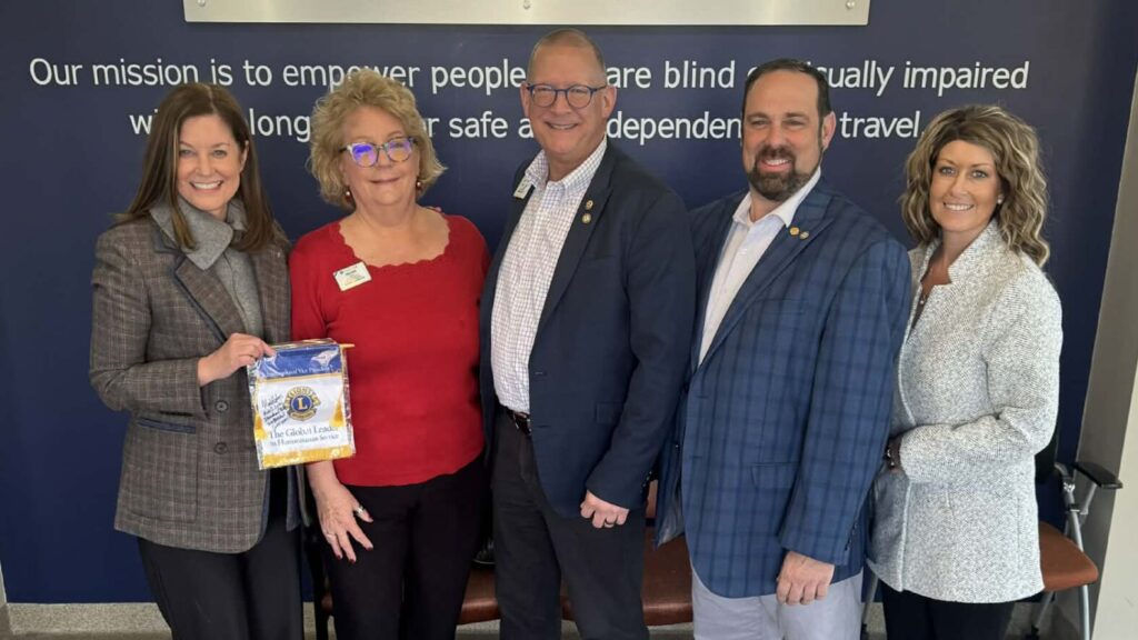 A group of people pose in front of the Leader Dogs for the Blind logo in the lobby of the canine center. From left to right: Melissa Weisse, Lyn Lyon, Mark Lyon, Justin Faber, Claudia Gregory and Shelly O'Henley.
