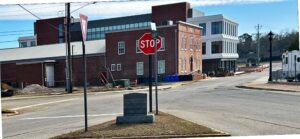 A photo from the intersection of the world’s smallest city block. The block is triangular-shaped, on it stands a marble marker and various street signs.