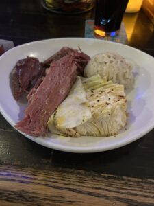 A white plate with corned beef, cabbage and mashed potatoes