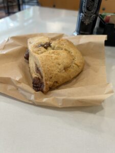 A lovely cinnamon scone sits atop it’s brown paper wrapper.