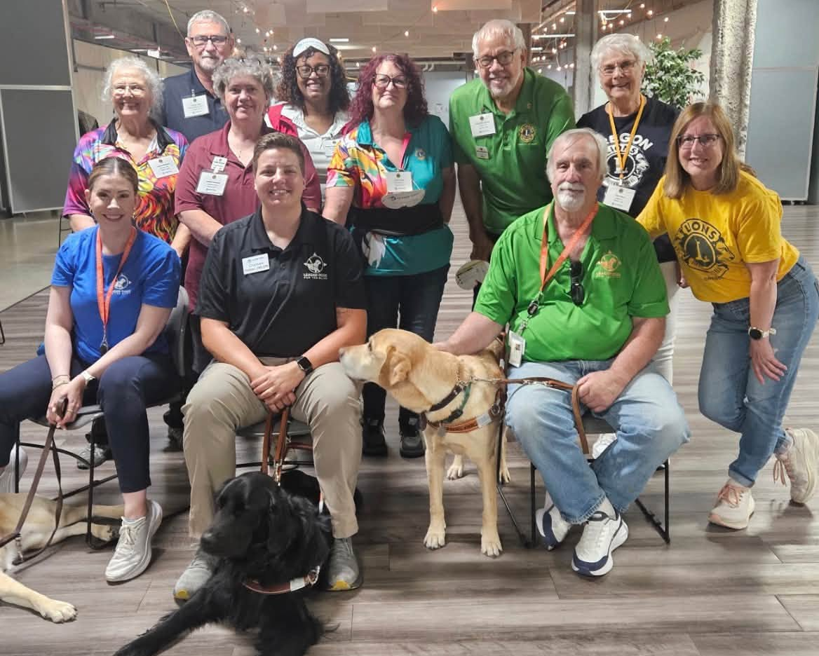 Group of Lions Club and service organization participants posing indoors with three guide or service dogs
