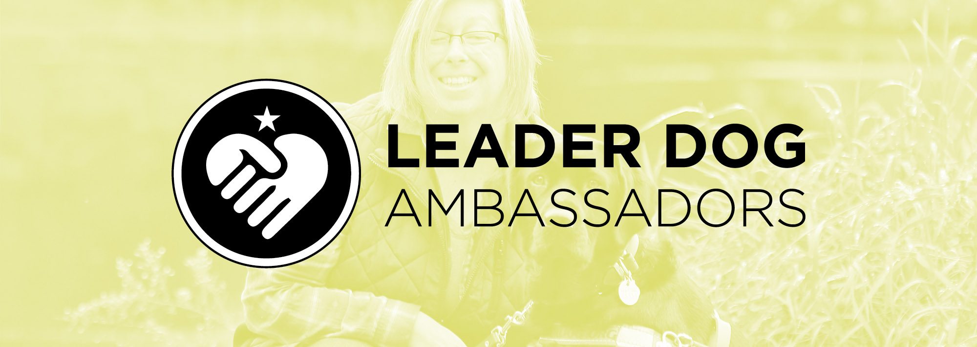 Light green colored image of a woman smiling and kneeling next to a black lab in harness. Over the image are the words Leader Dog Ambassadors with a circle icon of folded hands in a heart shape