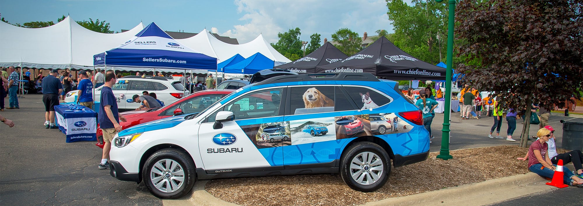 A Subaru Outback with photos of dogs and vehicles is on display at an event