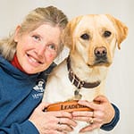 Marguerite leans her head against yellow lab Avery's head and smiles