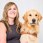 Lisa sits next to golden retriever Hopper, smiling
