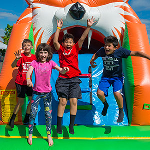 A group of kids jump up with smiling faces on an inflatable