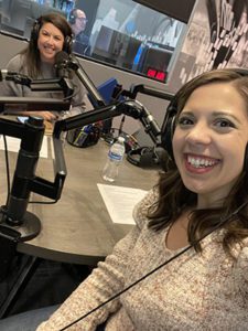 Christina takes a selfie of her and Leslie siting at a desk with podcast equipment