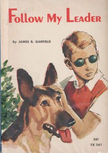 A book cover showing a drawing of the upper half of a young teenage boy. He has short, side-parted blond hair and is wearing round wire sunglasses, a white short-sleeve shirt and red sweater vest. His left hand is resting on the head of a German shepherd. The dog is tan and dark brown with large dark ears, its tongue is hanging out. The words “Follow My Leader” are in red across the top and “By James B. Garfield” underneath in black text.