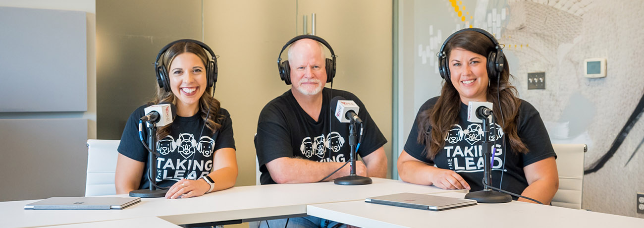 Christina, Tim and Leslie sit at a white table with microphones in front of them.
